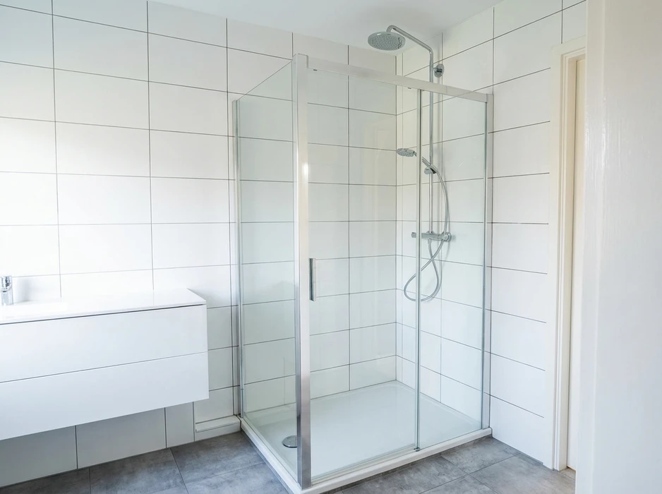 Salle de bain moderne minimaliste avec douche à l'italienne encadrée de parois en verre trempé et profilés aluminium chromé