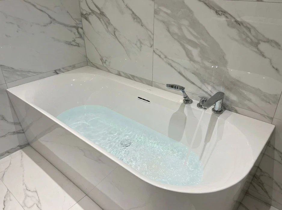 Baignoire encastrée rectangulaire blanche, partiellement remplie d'eau avec jets actifs
