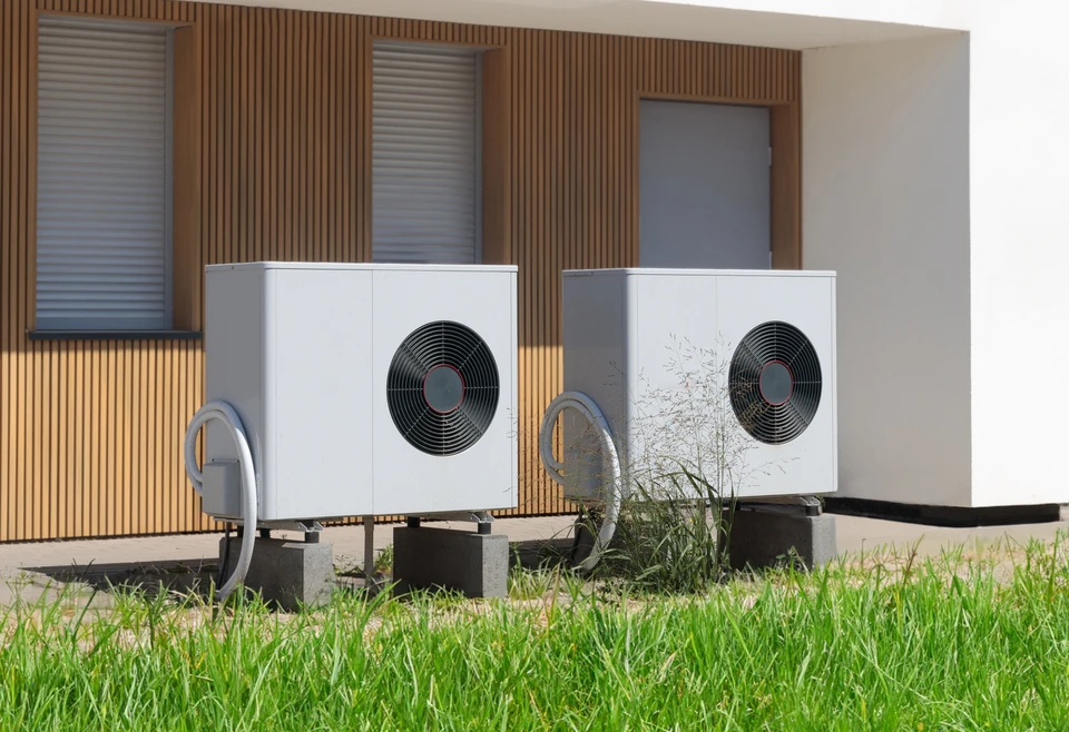 Deux pompes à chaleur air-eau installées à l'extérieur d'une maison moderne avec bardage bois vertical