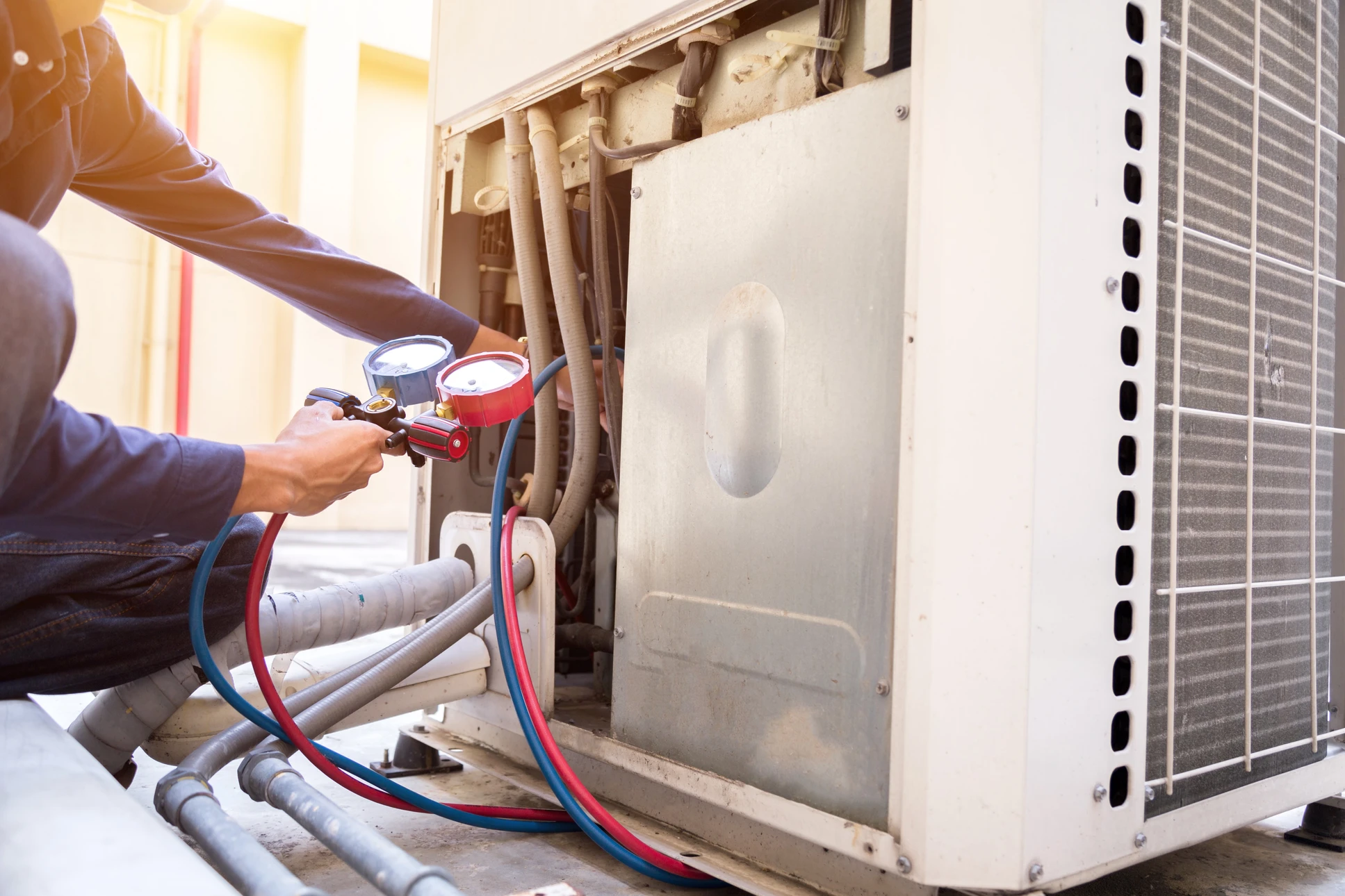 Technicien en uniforme blanc effectuant la maintenance d'un climatiseur mural split dans un intérieur résidentiel moderne aux murs blancs avec rideaux gris