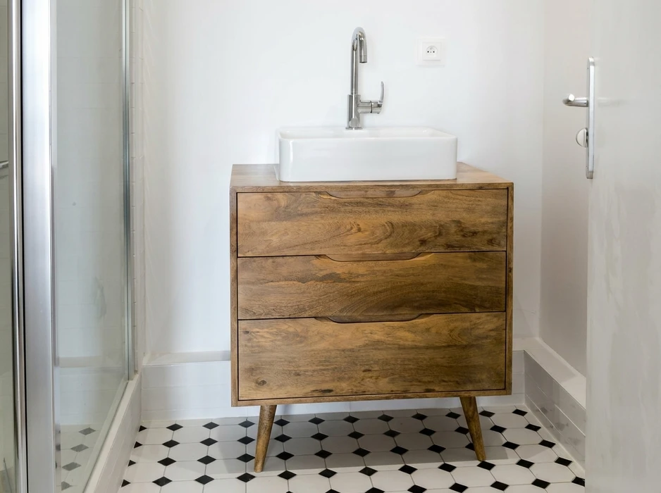 Salle de bain moderne avec meuble vasque en bois massif style scandinave, trois tiroirs à poignées encastrées, pieds fuseaux inclinés
