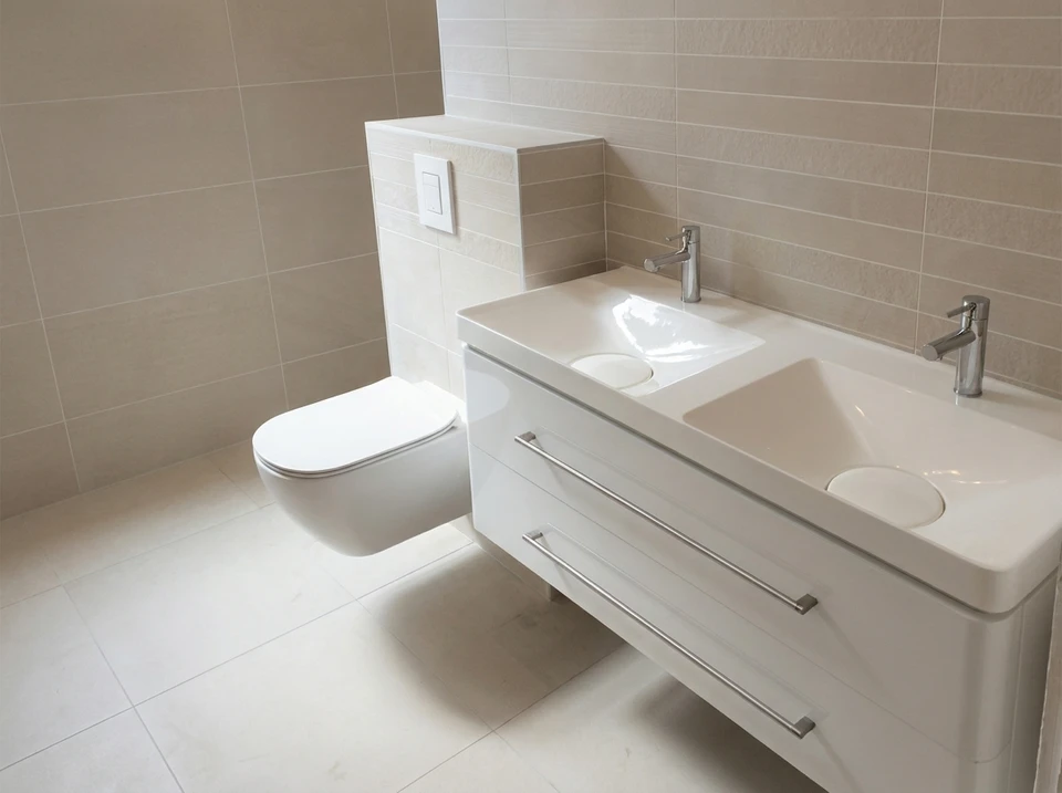 Plombier professionnel travaillant sur une installation de chauffage en intérieur, manipulant des outils sur un système complexe de tuyauterie cuivre et raccords
