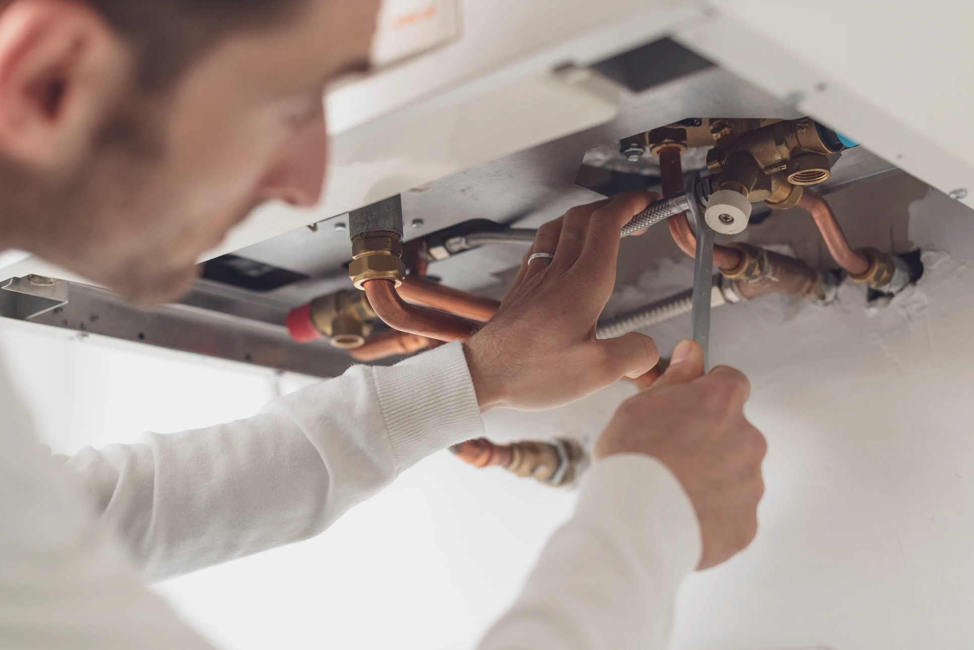 Technicien qualifi&eacute; en tenue professionnelle effectuant l'installation ou la maintenance d'une unit&eacute; int&eacute;rieure de climatisation (console murale ou cassette) dans un salon r&eacute;sidentiel moderne, mettant en &eacute;vidence le travail de pr&eacute;cision et la qualit&eacute; technique de l'intervention sur cet &eacute;quipement sp&eacute;cifique.