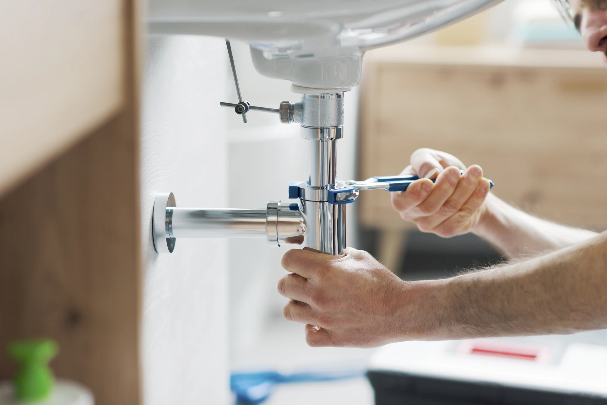 Int&eacute;rieur r&eacute;sidentiel, plombier en action sous &eacute;vier de cuisine