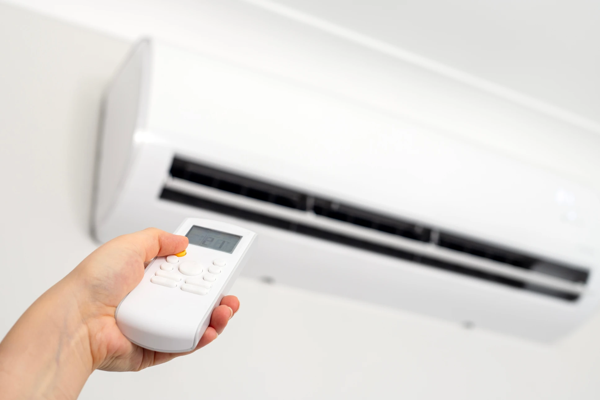 Technicien en climatisation effectuant la maintenance d'une unité de climatisation murale dans un intérieur moderne